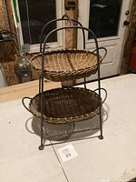 Front angle view of cast iron two-tier basket holder with woven baskets.