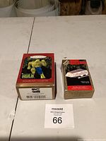 Photo of both collectible Christmas ornament boxes on a white table, showing packaging and branding.