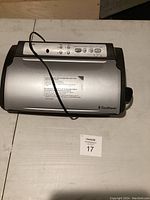 Top view of the silver FoodSaver vacuum sealer showing the control panel with buttons and indicator lights and the power cord placed loosely on top.