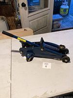 Side angle view of the blue hydraulic floor jack showing the handle and lifting arm.