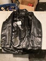 Front view of the full black leather jacket showing button closure and collar.