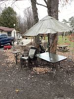 Full view of patio set including larger rectangular table with umbrella, seven stacked chairs, and smaller side table.