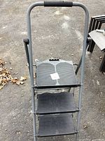 Front view of metal 3-step stool with black textured steps and handle grip