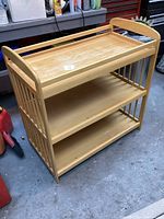 Front and side angle view of wooden storage shelves with three shelves and raised rails on top shelf.
