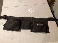 Black Husky tool belt laid out flat showing multiple pouches and compartments with red stitching.
