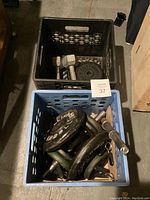 Two plastic crates containing weight plates and dumbbells on garage floor