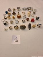 Photo displaying all costume rings and brooches of varied styles and colors arranged on a flat surface.