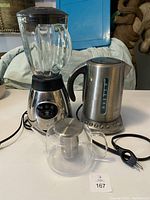 PC blender, Breville kettle and glass tea pot arranged together on white surface.