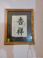 Framed Chinese calligraphy character painting under glass with wooden frame, black ink on cream textured paper.