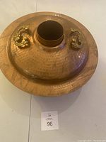 Top view of the hot pot lid showing hammered copper surface and brass handles with a central chimney.