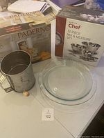 Overview of the flour sifter, pie plates, and boxed sets on table