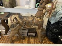 Front side view of the large replica carousel horse, showing saddle detail, tail, and head with carved mane.