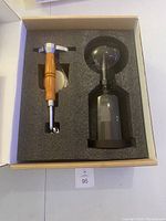 Top down photo of coffee siphon parts packed in foam inside box.