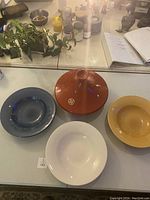 Overview of the tagine and three large ceramic bowls on a table with plants and various objects in the background.