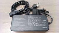 Top view of ASUS AC/DC Adapter showing detailed specifications, power ratings, and certification logos.
