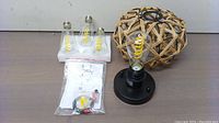 Chandelier base with one bulb in socket, wicker decorative cover, additional bulbs and hardware bag