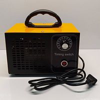 Front view of the yellow and black commercial ozone generator showing the timing switch dial, power button, and power cord.