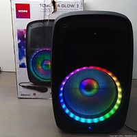 Front view of the ION Total PA Glow 3 Bluetooth speaker lit with multi-color LED ring, placed next to its original box.