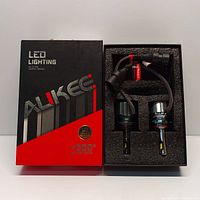 Box and contents showing Aukee branded packaging with two LED headlight bulbs and wiring harness in foam insert.