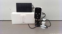 Photo showing the solar powered security camera alongside its box and the solar panel.