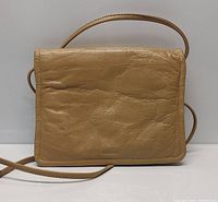 Front view of women's tan leather crossbody bag showing textured leather surface, creases, and simple design.