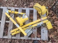 Two yellow loading dock lights with mounting brackets and cords, placed on a wooden pallet outdoors among leaves.