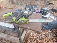 Photo of a green and black Poulan chainsaw with a metal guide bar and chain placed on a metal stand outdoors, autumn leaves on the ground.