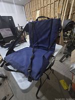 Pair of foldable bleacher chairs in navy blue fabric with straps lying on a table in a storage area.
