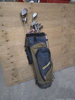 Photo of golf clubs standing in Spalding branded golf bag, showing multiple clubs with steel shafts and bag front pocket.