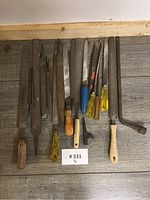Top view of assorted metal files and hand tools neatly arranged showing variety of shapes and handle types