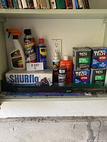 Shelf with multiple auto care products including oil filters, tire foam, lubricants, wiper blade, and cleaning bottles