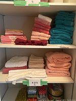 Photo of shelves with neatly folded assorted bathroom towels and washcloths in varied colors.