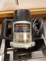 Top/front angle view of Black & Decker router showing front handle and power cord coiled beside it.