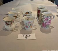 Top view of all seven floral bone china tea and coffee cups arranged in a group on a light surface.