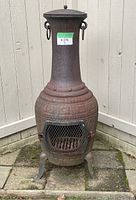 Front view of the chiminea showing the vent door with mesh and decorative pattern on the base