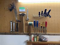 Full view of mounted tools on pegboard showing hammers, clamps, chisels, wrenches, squares and other hand tools