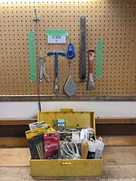 Overall view of handheld tool lot with yellow toolbox and pegboard mounted tools