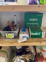 Photo of a box of Cobex sweeping compound, green box of Comfo II respirator masks, box of MCD nitrile gloves, and plastic container with various packing materials.