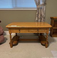 Front-side view of the vintage wooden coffee table showing drawer and twisted legs.