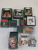 Overall photo showing 12 Hallmark Christmas collector's ornaments in boxes and packaging on a white surface.
