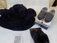 Photo showing black bathrobe, Isotoner slippers on box, Skechers shoe box and shoes, Vitabath towel package on bed