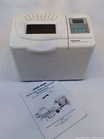 White Black and Decker bread maker with control panel and user manual placed in front