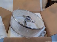 Top-down view showing the white fabric shade with chrome edge and central mounting hardware inside the shade.