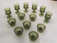 Overview of all 13 items including 6 claret wine glasses and 7 sherbet cups in green glass with thumbprint pattern.