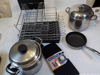 Metal dish strainer with multiple compartments, black plastic tray base, stainless steel stock pot with lid, small Lagostina frying pan, stainless steel steamer insert, black drying mat with packaging