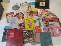 Photo showing a large assortment of vintage softcover cooking books arranged together, highlighting the condition and quantity.