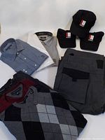 Lot contents showing folded sweaters, button shirts, pants, and Munro golf hats