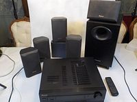 Full set showing AV receiver, subwoofer, center speaker, four satellite speakers, remote control, and antenna.