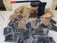 Floor mount black metal corker with red handle and wooden base. Several bags of natural corks and many black heat shrink caps arranged in front of it.