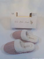 Pink knit textured slippers with white faux fur lining and U.S. Polo Assn. box